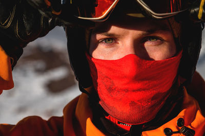 Young man looks directly into the camera, close-up of the eyes. hands holding ski mask or goggles