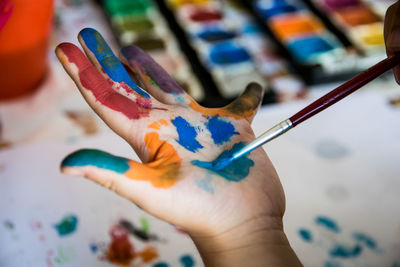 Cropped hands of child holding paintbrush