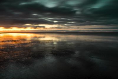 Scenic view of sea against dramatic sky during sunset