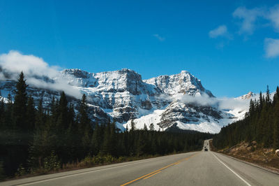 Road amidst snowcapped mountains against sky