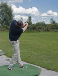 Full length of man playing guitar on golf course