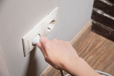 A young woman inserts a plug into a socket. a young woman plugs a charger or electrical appliance