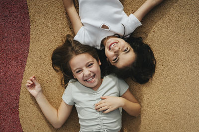 Directly above view of happy sisters lying on footpath