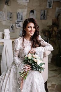 Portrait of smiling young woman standing against white wall