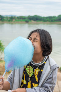 Girl eating cotton candy against lake