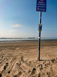 Road sign on beach against sky