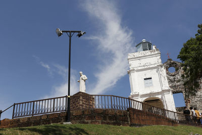 Low angle view of street light by building against sky