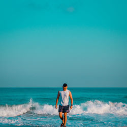 Rear view of man looking at sea against clear sky