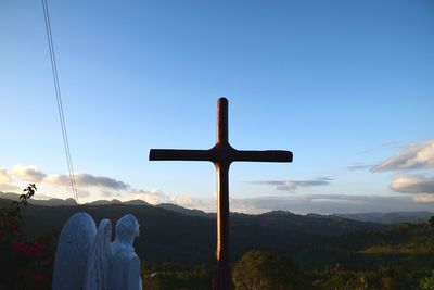 Low angle view of cross on mountain against sky