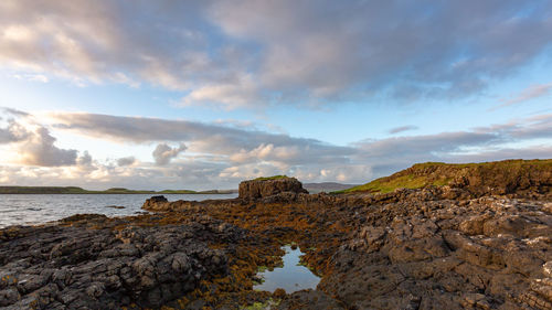 Rock formations on shore against sky