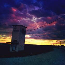 Low angle view of power lines against cloudy sky