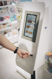 Cropped hand of male customer using kiosk at pharmacy store