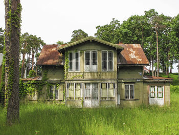 Abandoned building by trees against sky