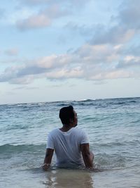 Rear view of man at beach against sky