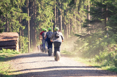 Rear view of people riding bicycles on road