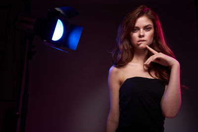 Portrait of young woman standing against wall