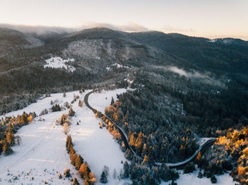 Winter in the mountains.snow covered trees from above. scenic aerial landscape with road at sunrise.