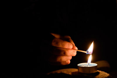 Close-up of hand holding illuminated candle