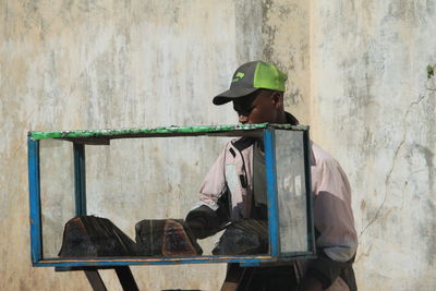 Side view of man sitting on wall