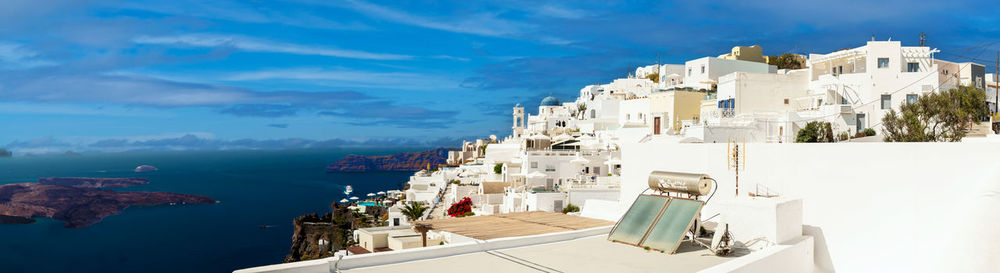 Buildings by sea against sky