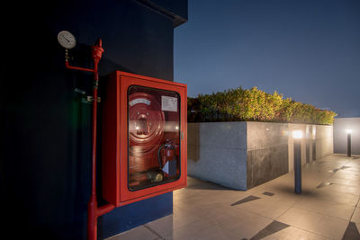 Illuminated lamp by building against sky