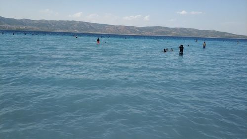 People in sea against sky