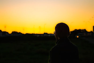 Portrait of silhouette man standing against orange sky