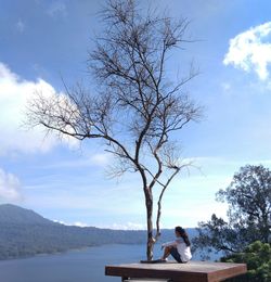 Young woman sits with a view of the lake and blue sky