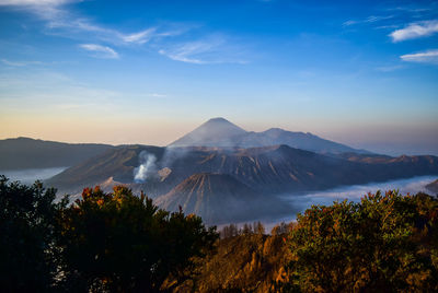 Scenic view of volcanoes against blue sky during sunset