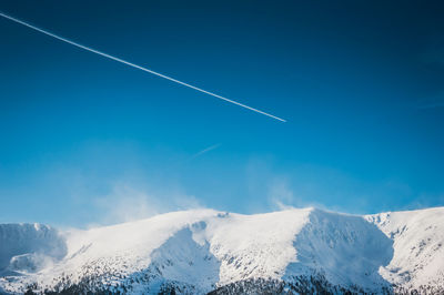 Aerial view of snowcapped mountains against blue sky