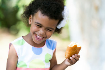 Smiling girl eating food in park