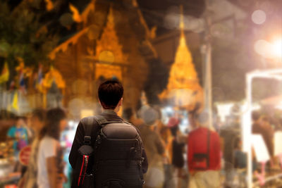 Rear view of people standing in city at night