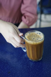 Cropped woman's hand holding a mug of malaysian coffee