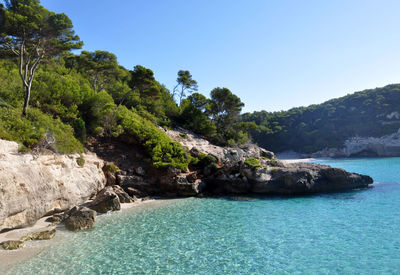 Scenic view of mountain by sea against clear blue sky