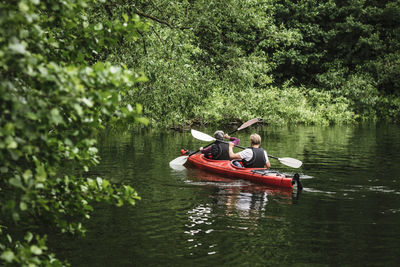 Rear view of senior man and woman kayaking in sea during training course