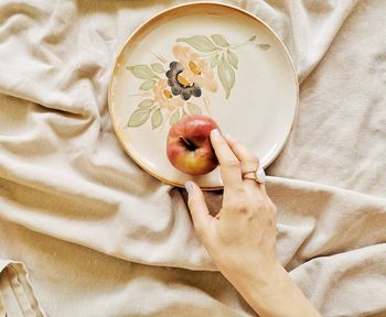 High angle view of hand holding apple on bed