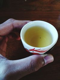 Close-up of hand holding tea cup on table