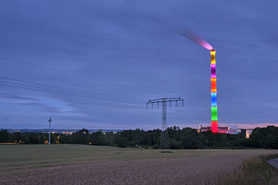 Electricity pylon on field against sky at dusk