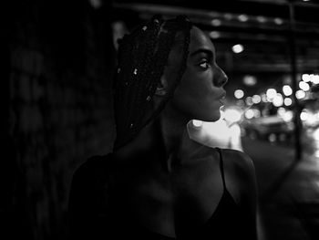 Close-up of woman looking away while standing in city at night