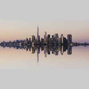 Cityscape reflecting in river at dusk