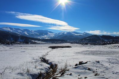 Scenic view of snow covered mountains against bright sun