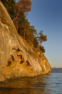 Rock formations by sea against clear sky