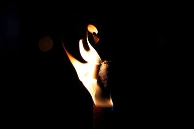 Close-up of lit candle in darkroom