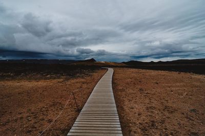 View of dirt road against cloudy sky