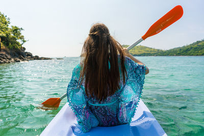 Woman kayaking on sea against sky