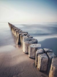 Wooden posts on beach against sky