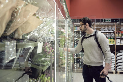 Man standing by flowers on display at supermarket