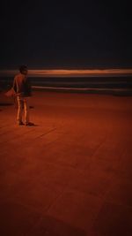 Man standing on beach against sky at night