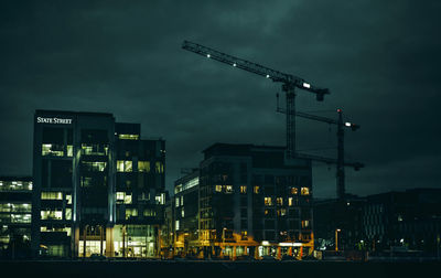 Illuminated buildings and crane in city at night