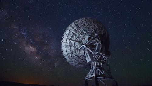 Low angle view of radio telescope against star field at night